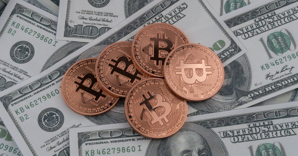 Bitcoins und Hundertdollarscheine im Hintergrund