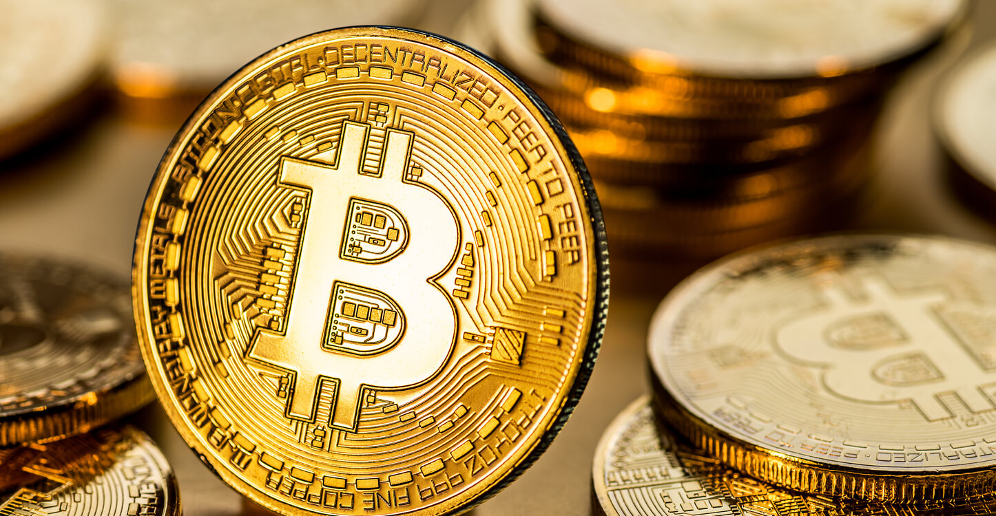Glänzende physische Bitcoins auf goldenem Hintergrund