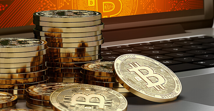 Stapel von Bitcoins auf einem Computer mit Bitcoin-Logo auf dem Bildschirm